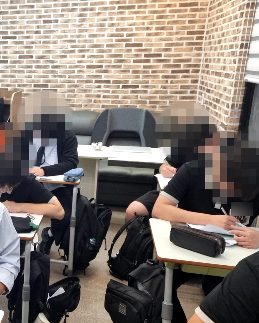 벽돌 벽 강의실에서 학생들이 문제를 풀고 있는 실제 수업 장면